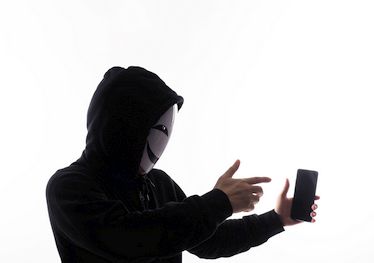 Hacker Anonymous and face mask with smartphone in hand.
